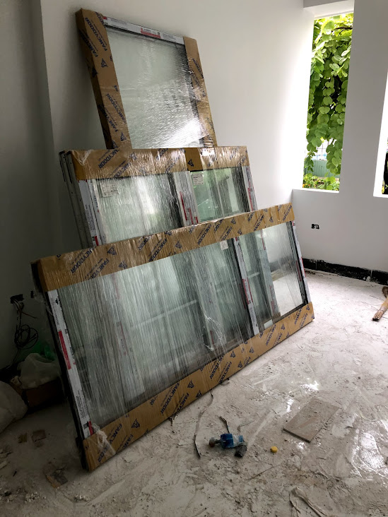 Cửa kính khung nhôm mới được bọc nilon đặt trong phòng đang xây dựng